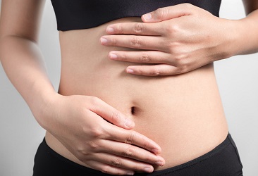 Junge schwangere Frau tastet ihren Bauch ab